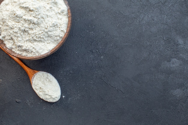 Photo top view white flour inside plate on dark background dough bake oven cake pie biscuit