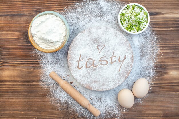 Photo top view white flour with eggs and rolling pin