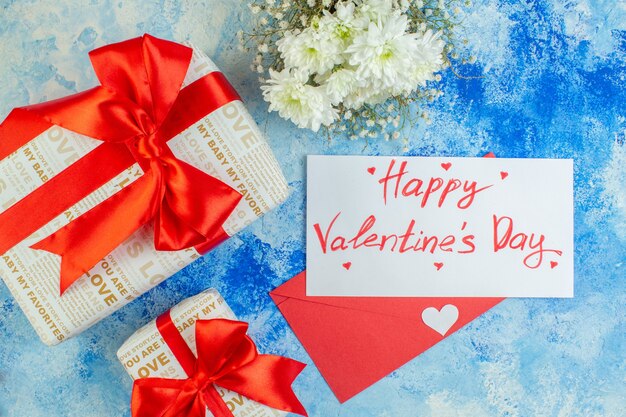 top view white flowers gifts happy valentines day written on letter red envelope on blue table