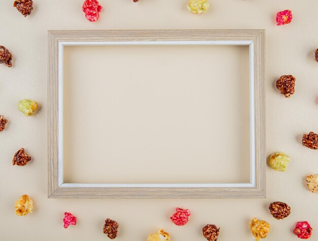 top view of white frame with skittles popcorn around on white background with copy space