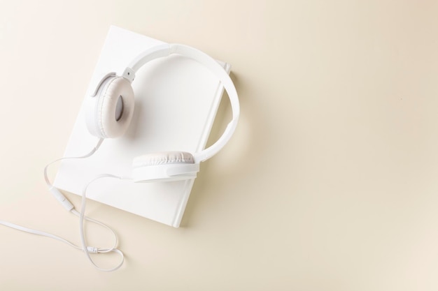 Top view of white headphones and notebooks on background with copy space Flat lay