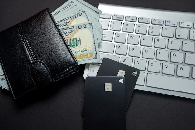 Top view of white keyboard money dollars wallet and credit cards isolated on table