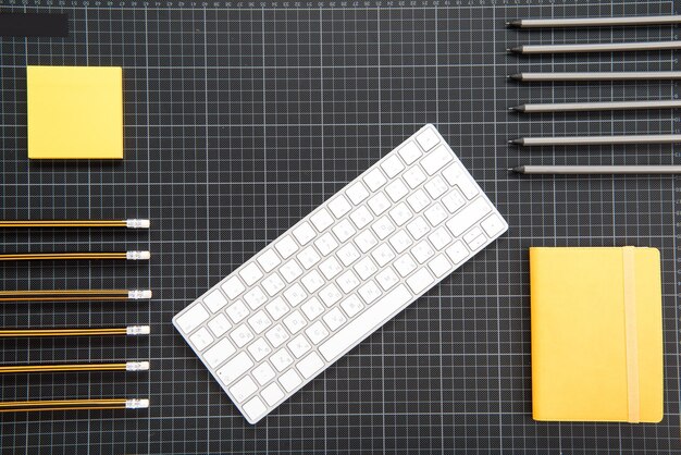 Top view of white keyboard and organized office supplies on black