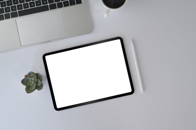 Top view white office desk with digital tablet laptop glasses and coffee cup