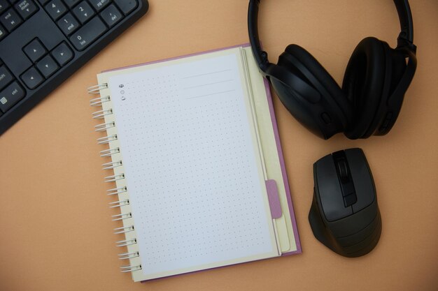 Top view of white office desk with notebook keyboard mouse headphones