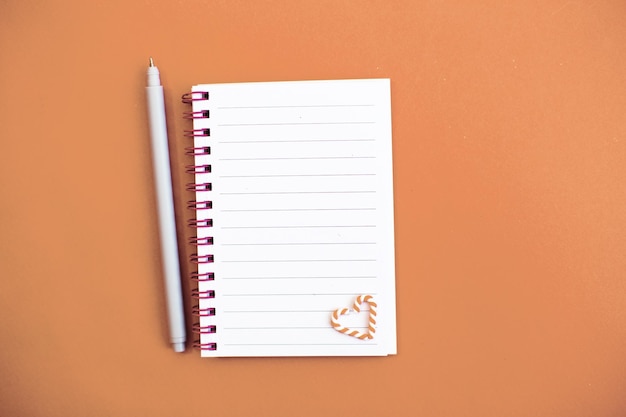 Top view of white paper blank notebook for writing wish list and planning goals tasks and target for 2024 new year writing to do list on Peach Fuzz background Color of the year 2024