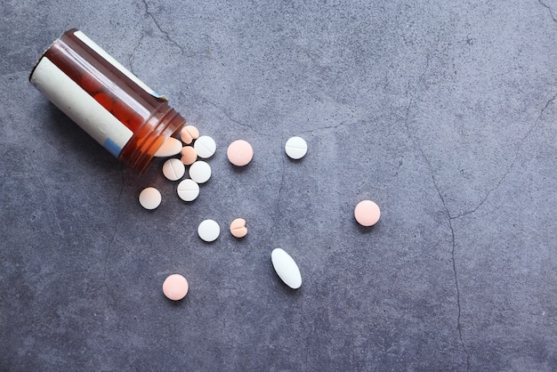 Top view of white pills spilling on black background