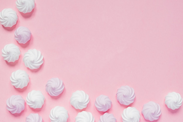 Photo top view of white and pink twisted meringues  on pink background