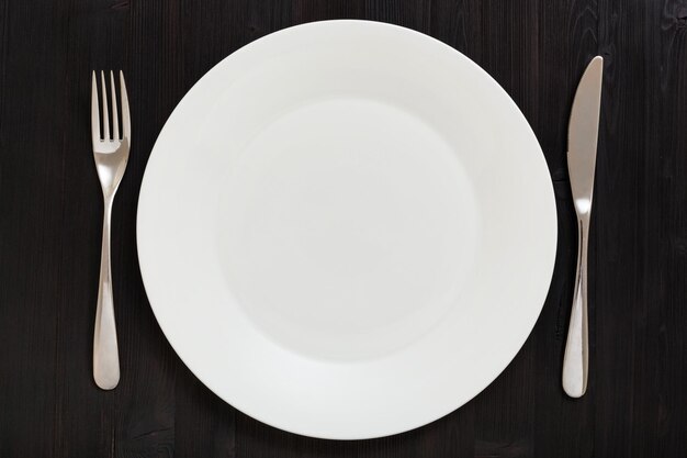 Вид сверху на белую тарелку с ножевой ложкой в темноте