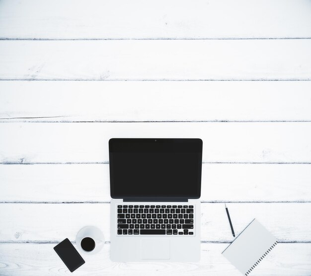 Top view of a white wooden table with a laptop and accessories with copyspace