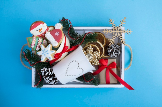 Top view of white wooden tray with Christmas presents on the blue background