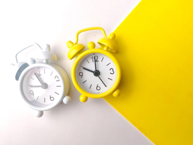 Top view white and yellow alarm clock on a white and yellow background with copy space