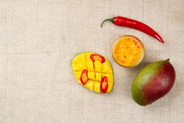 Photo top view of whole mango whole chili pepper sliced hot pepper cutted half of mango and spicy mango