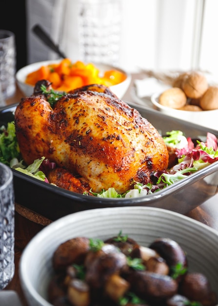 Вид сверху на целую жареную курицу, подаваемую со свежим салатом в черной сковороде Концепция приготовления празднования Дня Благодарения или семейного ужина
