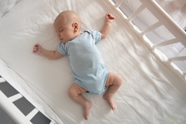 상위 뷰 광각 수면 신생아는 침대 팔과 다리를 뻗은, 아기 수면에 놓여 있습니다