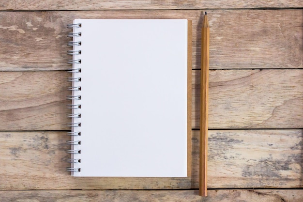 Top view with blank empty notepad and pencil on wood table