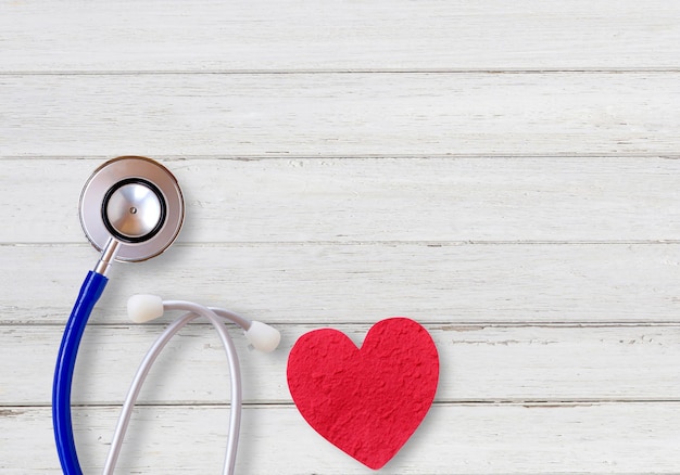 Top view with blue stethoscope and red heart on white wood table in office workplace