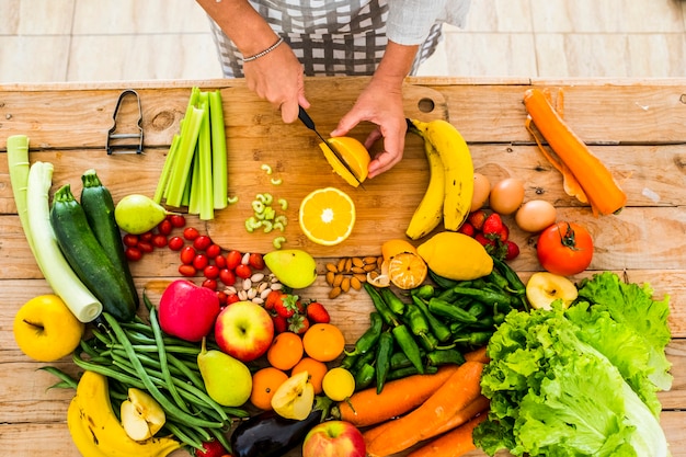 Top view of woman chef cutting and preparing healthy natural food on a wooden table