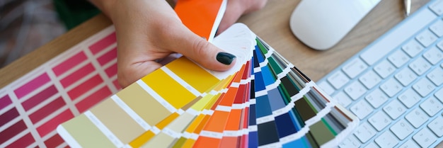 Top view of woman designer holding fan of colourful samples in hand designer searching proper