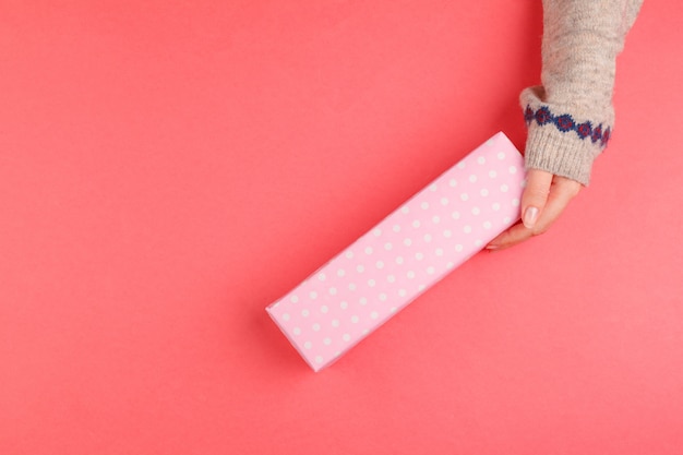 Top view of woman hands holding gift box on pink background