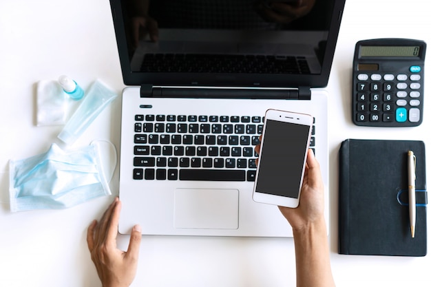 Top view of woman hands holding smart phone on desk at office, copy space. Protection against infectious virus, bacteria and germs concept