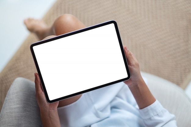 Top view  of a woman holding black tablet pc with blank white desktop screen