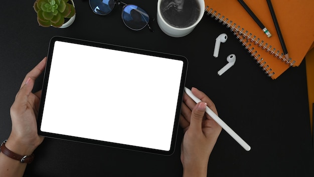 Top view of woman holding digital tablet and stylus pen on black table