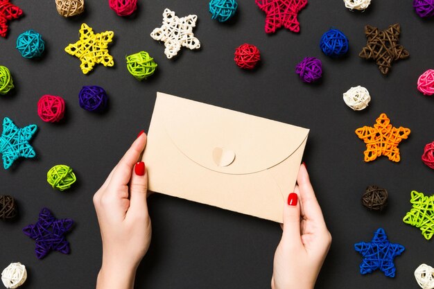 Top view of woman holding an envelope on background made of holiday decorations christmas time