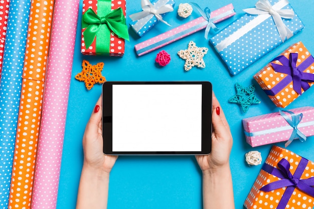 Top view of woman holding tablet in her hands on blue background 