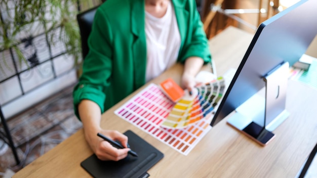 Top view of woman interior designer working with fan of colourful samples in office female