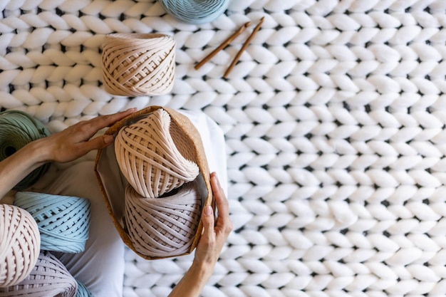 Foto designer di vestiti lavorati a maglia da donna vista dall'alto che mette il filo del nastro nell'organizzazione dell'immagazzinamento della casa del cestino