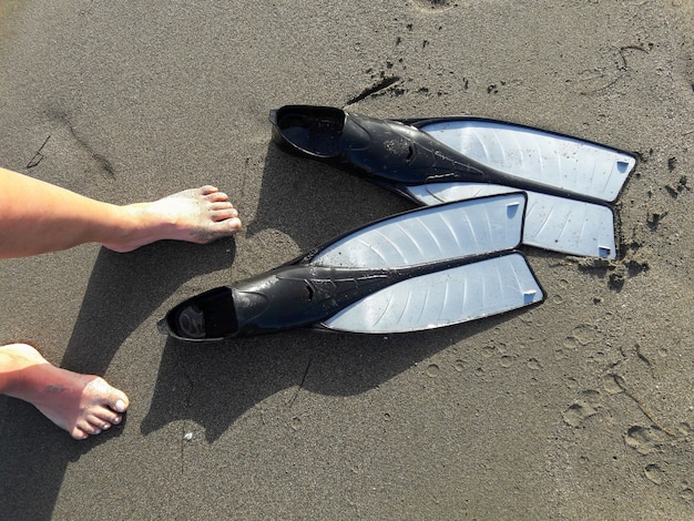 Top view of woman leggs and diving pins on the sandy coast