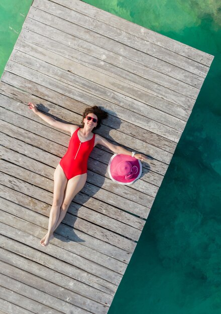 Top view of woman lying down on wooden pier at sunny summer day in cancun mexico young sexy woman in