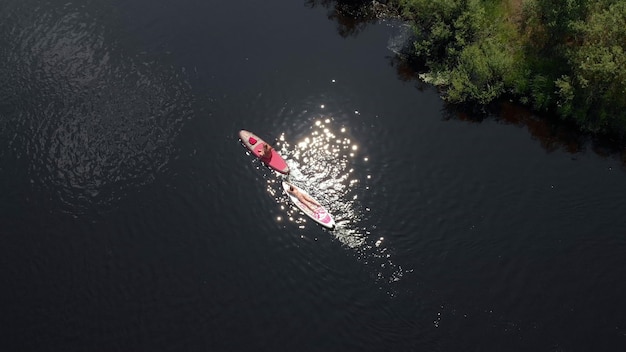 Photo top view woman paddle sup surfing the river. concept relaxation and vacation. top view of tourists on lake with sup-boards. beautiful clear water with people floating on boards engaged in sup-surfing