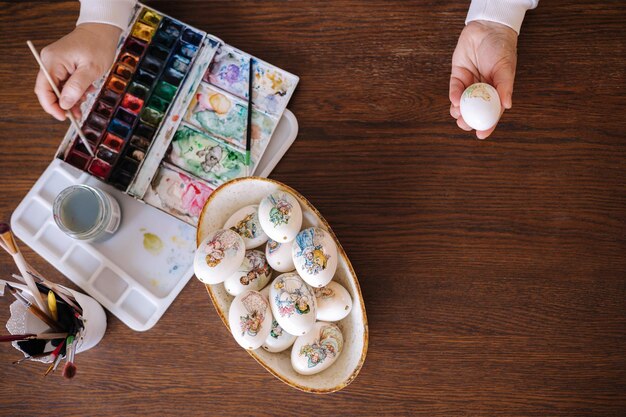 Top view of woman painting a water colors on fantasy chicken eggs for easter egg festival female