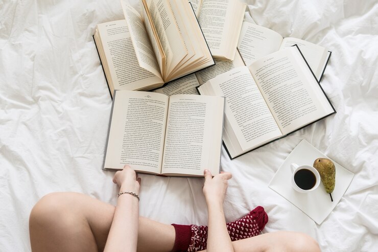 Photo 白いベッドカバーの本を読んでいる女性のトップビュー