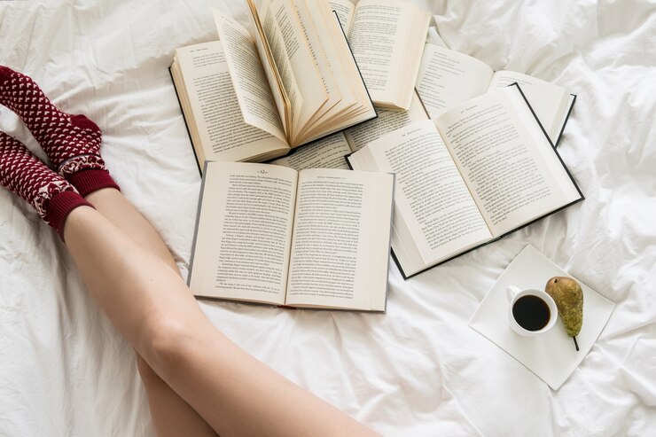 Photo 白いベッドカバーの本を読んでいる女性のトップビュー