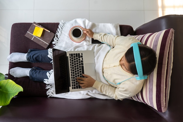 Top view woman relaxing wear headphones with using laptop computer and drinking coffee