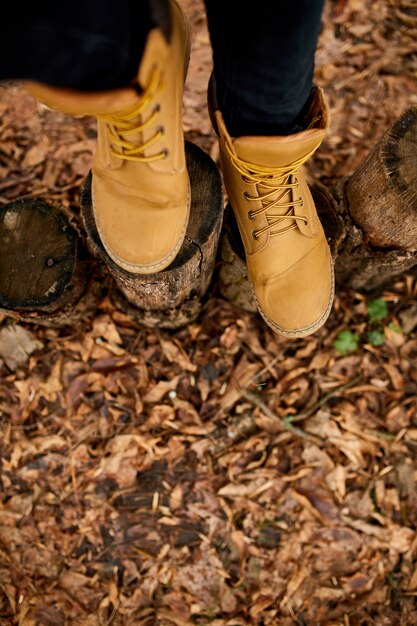 Top view woman standing with hiking mountain boots on autumn leaves and wood background