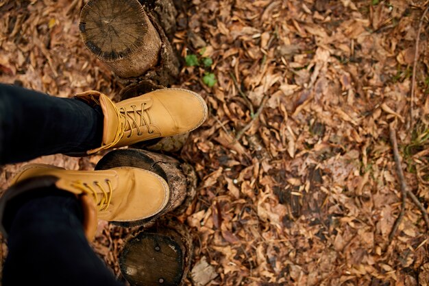 Photo top view woman standing with hiking mountain boots on autumn leaves and wood