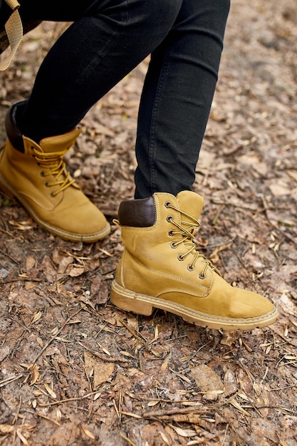 Top view woman standing with hiking mountain boots on autumn leaves and wood