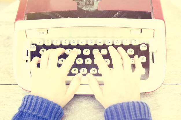 Top view of a woman typing on a typewriter vintage photo effect