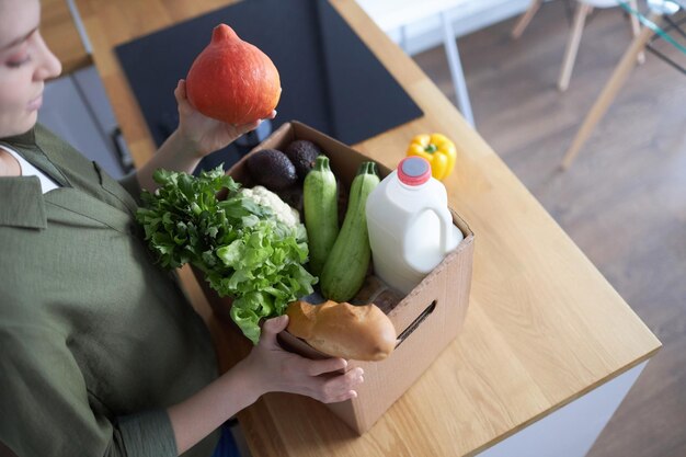 Top view of woman unpacking fresh groceries in kitchen