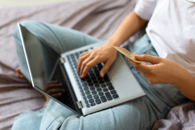 Top view of a woman with credit card in hands in front of laptop monitor