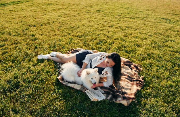 トップビュー彼女の犬と一緒に女性は晴れた日中にフィールドで楽しんでいます