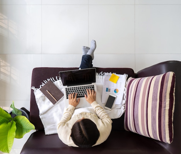 Photo top view woman working on laptop on the sofa in the house