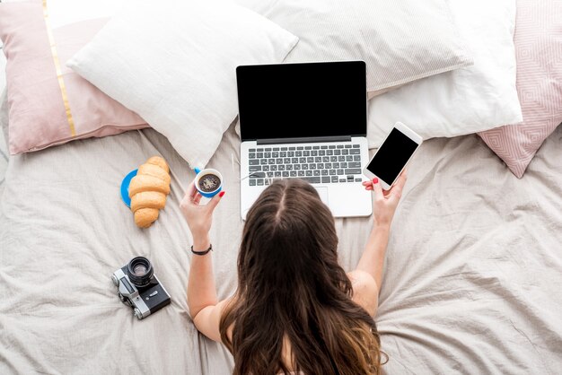 Photo top view on the woman working with laptop on the bed