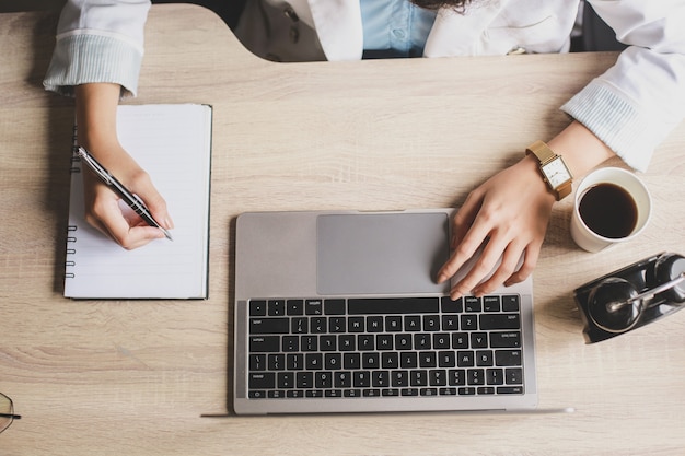 Top view of woman working on a wooden office desk