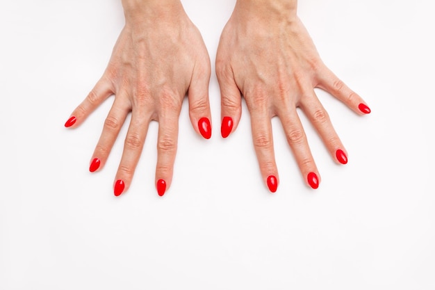 Vista dall'alto delle mani di una donna con una perfetta manicure rosso brillante professionale smalto rosso per unghie