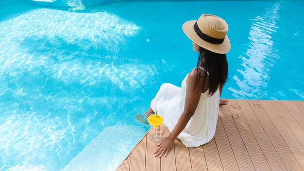 Top view at women with hat and a cocktail by swimming pool with copy space